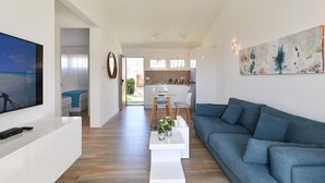 Ein modernes Wohnzimmer mit Flachbildfernseher, einem blauen Sofa und einem Couchtisch mit einer Pflanze.