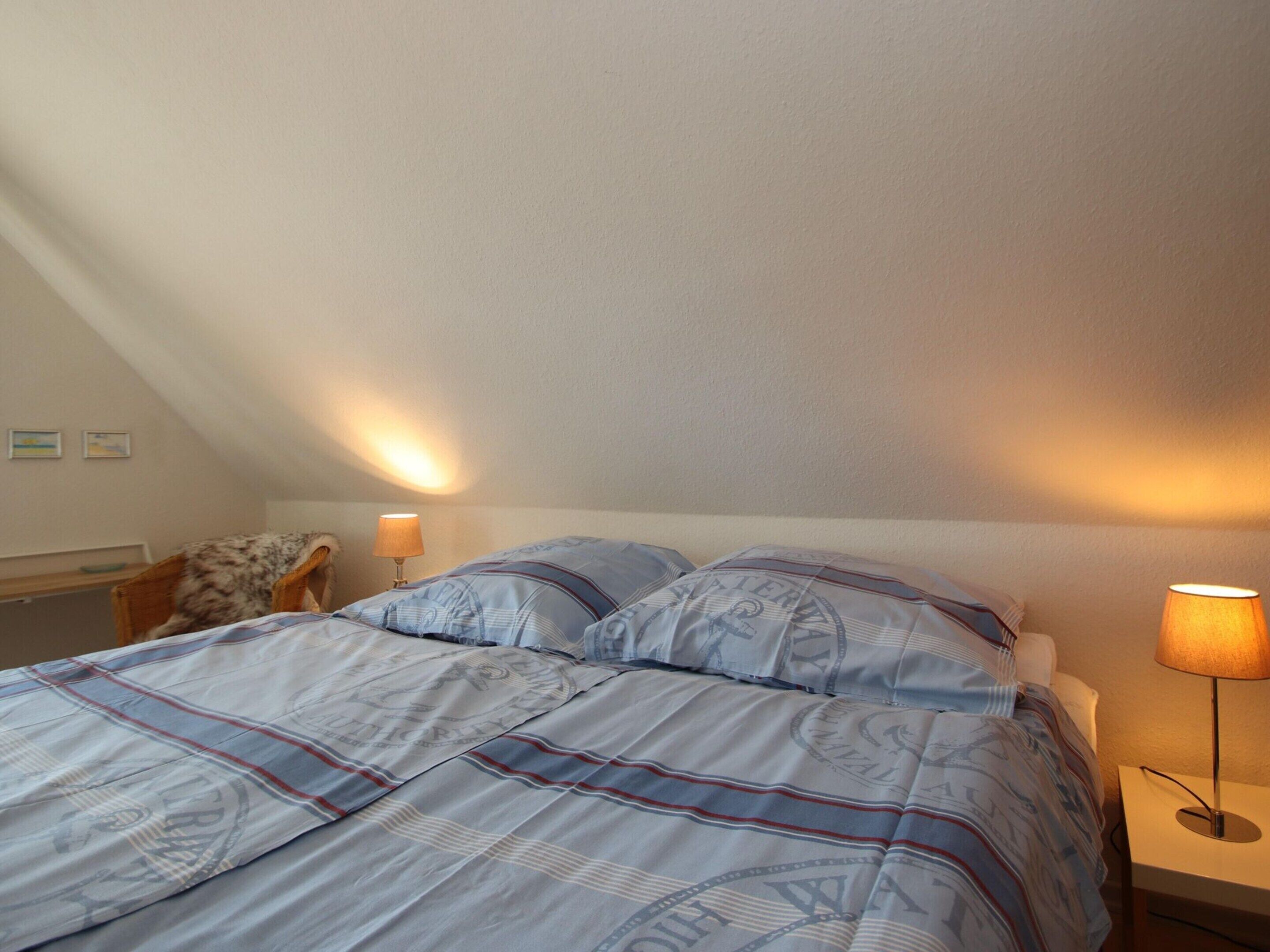 A bedroom with a bed, two bedside lamps, and a nightstand.