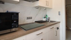A modern kitchen with a built-in oven, a microwave, and a stainless steel range hood. - House in Dornumersiel Near Sandy Beach (Dornum)