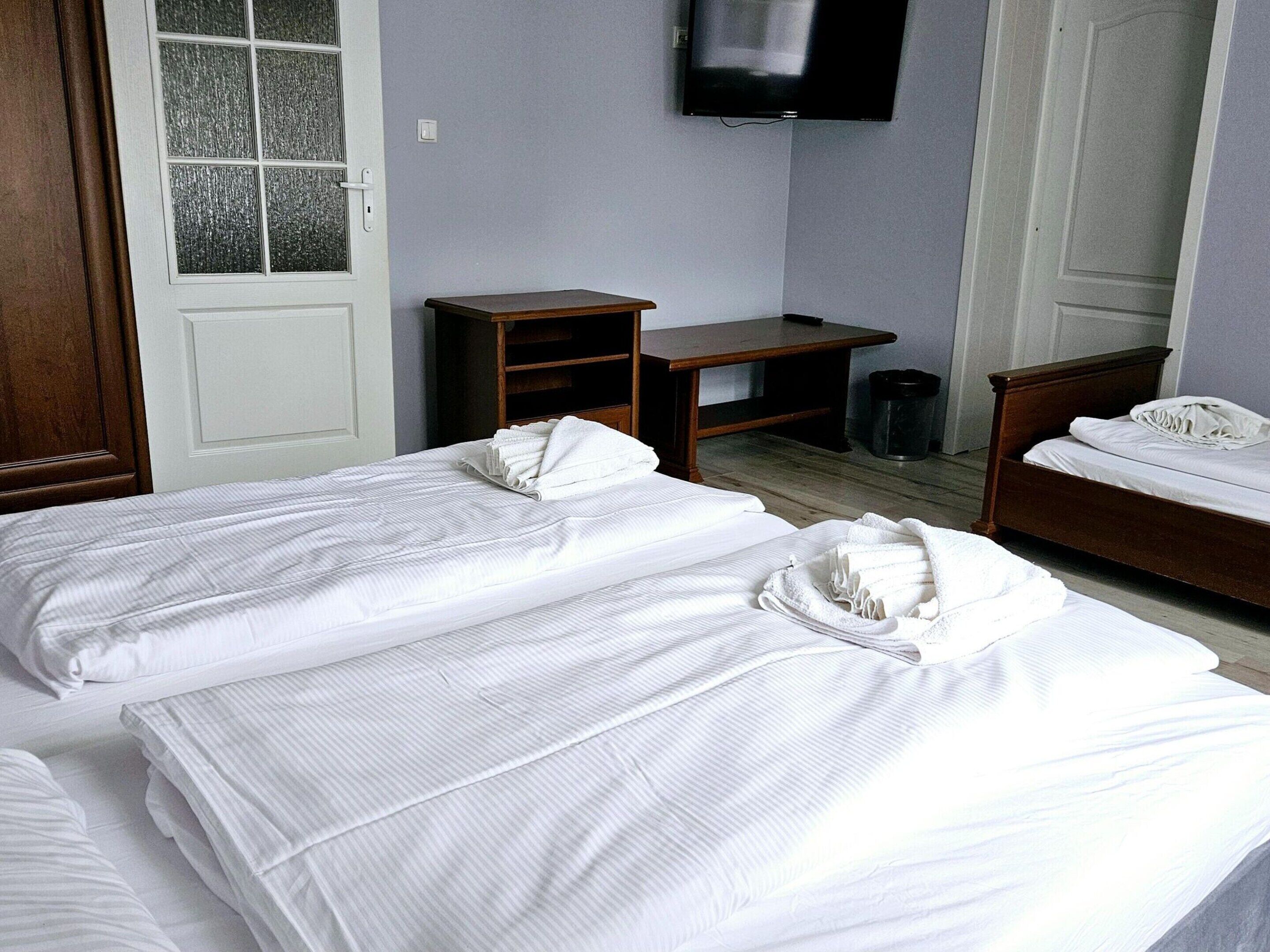 A hotel room with two beds, a desk, a TV, and a trash can.