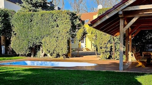Un jardin avec une piscine, une pergola en bois et une pelouse bien entretenue.