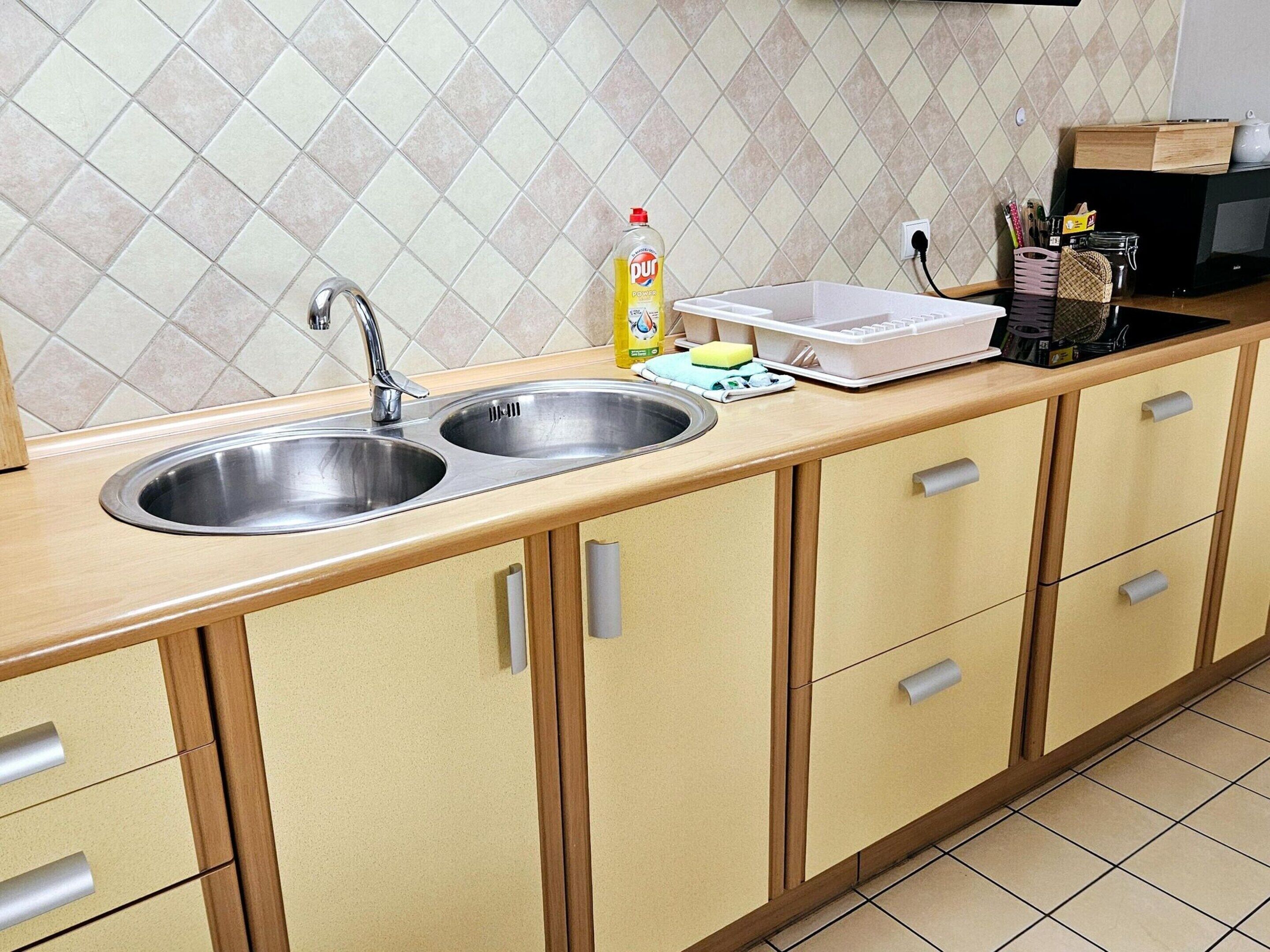 A kitchen with two stainless steel sinks, a microwave, and wooden cabinets.