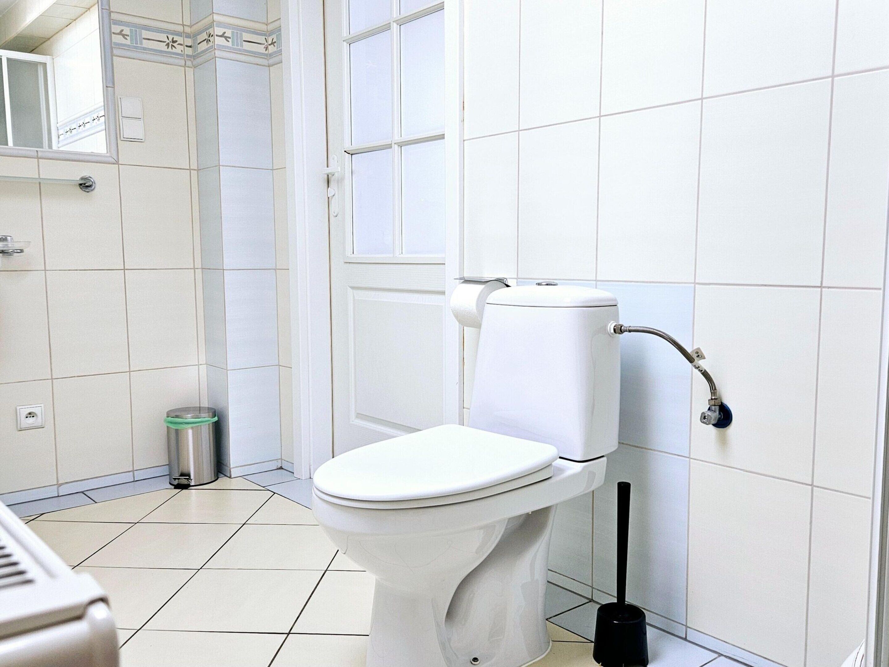 Ein Badezimmer mit Toilette, einem Händetrockner und einem Mülleimer.