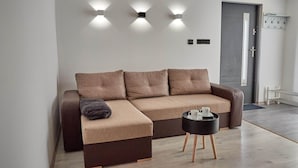 Una sala de estar moderna con un sofá modular, una mesita auxiliar negra y luces instaladas en la pared.