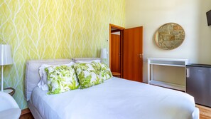 Een hotelkamer met een bed, een bureau, een lamp en een wand met behang.