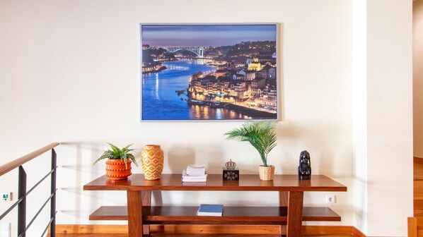 Een houten bank met decoratieve items en daarboven een lijst met een foto van een stadsgezicht.