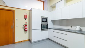 Een moderne keuken met witte kastjes, een inbouwoven en een waterkoker op het aanrecht.