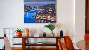 A dining area with a view of a cityscape at dusk, a wooden table, chairs, and decorative items.