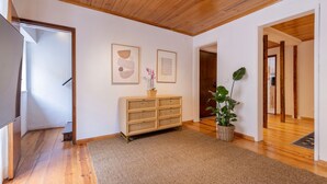 Una habitación amplia con piso de madera, una mesa consola de ratán y dos obras de arte enmarcadas en la pared.