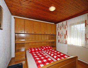 A bedroom with a wooden bed, a large wardrobe, and a window with curtains. - Apartment in Hippach im Zillertal With a View (Hippach)