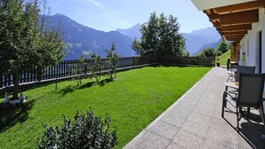Une terrasse avec vue sur les montagnes, une clôture en bois et une table avec des chaises.