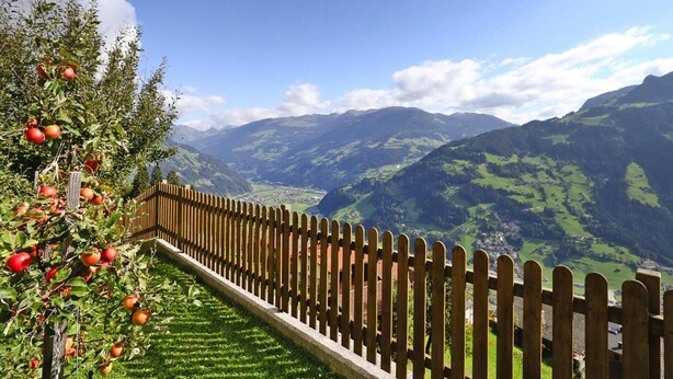 Une clôture en bois qui mène à une vallée, avec des montagnes en arrière-plan.