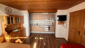 Une cuisine au sol en bois, dotée de placards, d’un four à micro-ondes et d’un téléviseur fixé au mur.