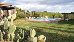 Ein Poolbereich mit Liegestühlen, einem Kakteengarten und einer Pergola.
