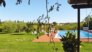Ein Garten mit Pool, einer Pergola und einem Rasen.