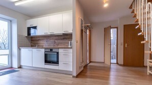 A modern kitchen with white cabinets, a built-in oven, and a wooden backsplash. - Tolle Ferienwohnung in St.peter Ording (St. Peter-Ording)