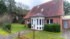 A two-story house with a red-tiled roof, a small porch, and a number '12' on the side. - Tolle Ferienwohnung in St.peter Ording (St. Peter-Ording)