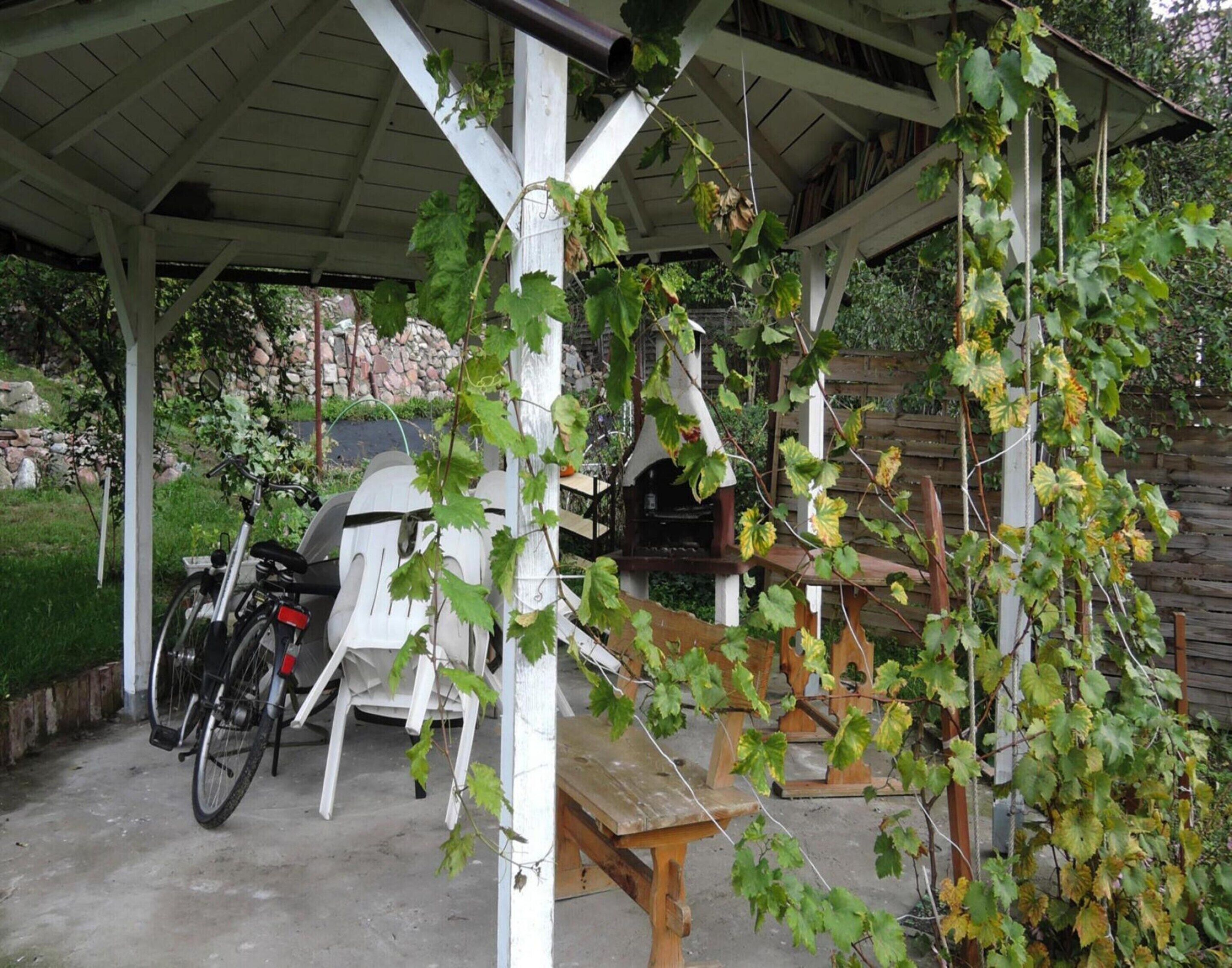 A covered outdoor area with a bicycle, a bench, and a grill.