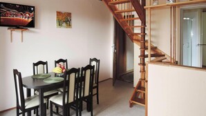 A dining area with a wooden staircase leading to a second floor. - House in Wiselka Near Baltic Sea Beach (Międzyzdroje)