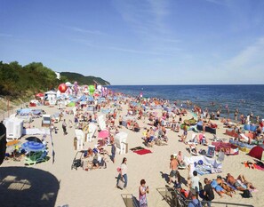 Une plage bondée, avec de nombreux parasols et des chaises de plage.