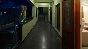 Un couloir doté d’un sol sombre, d’un paillasson bleu et d’un escalier menant à un autre espace.
