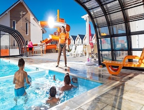 Un’area piscina con scivolo, lettini prendisole e una zona relax coperta.