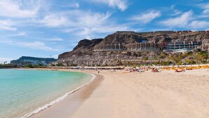 A beach with a hotel in the background. - Holiday Home in Puerto Rico With Garden (Mogan)