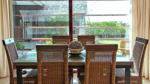 A dining area with a glass table and wicker chairs, a decorative bowl on the table, and a view of greenery outside. - Holiday Home in Puerto Rico With Garden (Mogan)
