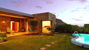 A modern house with a stone exterior, a swimming pool, and a well-maintained lawn. - Holiday Home in Puerto Rico With Garden (Mogan)