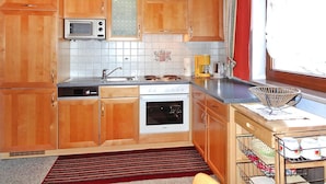 Une cuisine avec des armoires en bois, un four à micro-ondes, une cuisinière et un évier.