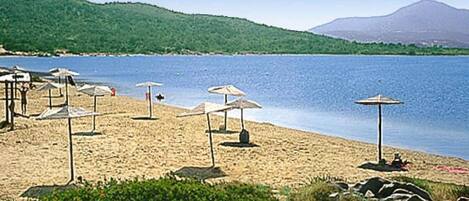 A beach with umbrellas and a mountain in the background.