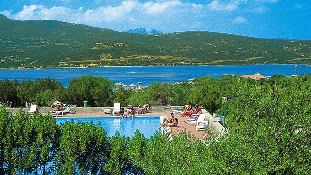 A pool area with lounge chairs and a view of the sea and hills. - Apartment in Porto Rotondo Near Sandy Beach (Olbia)