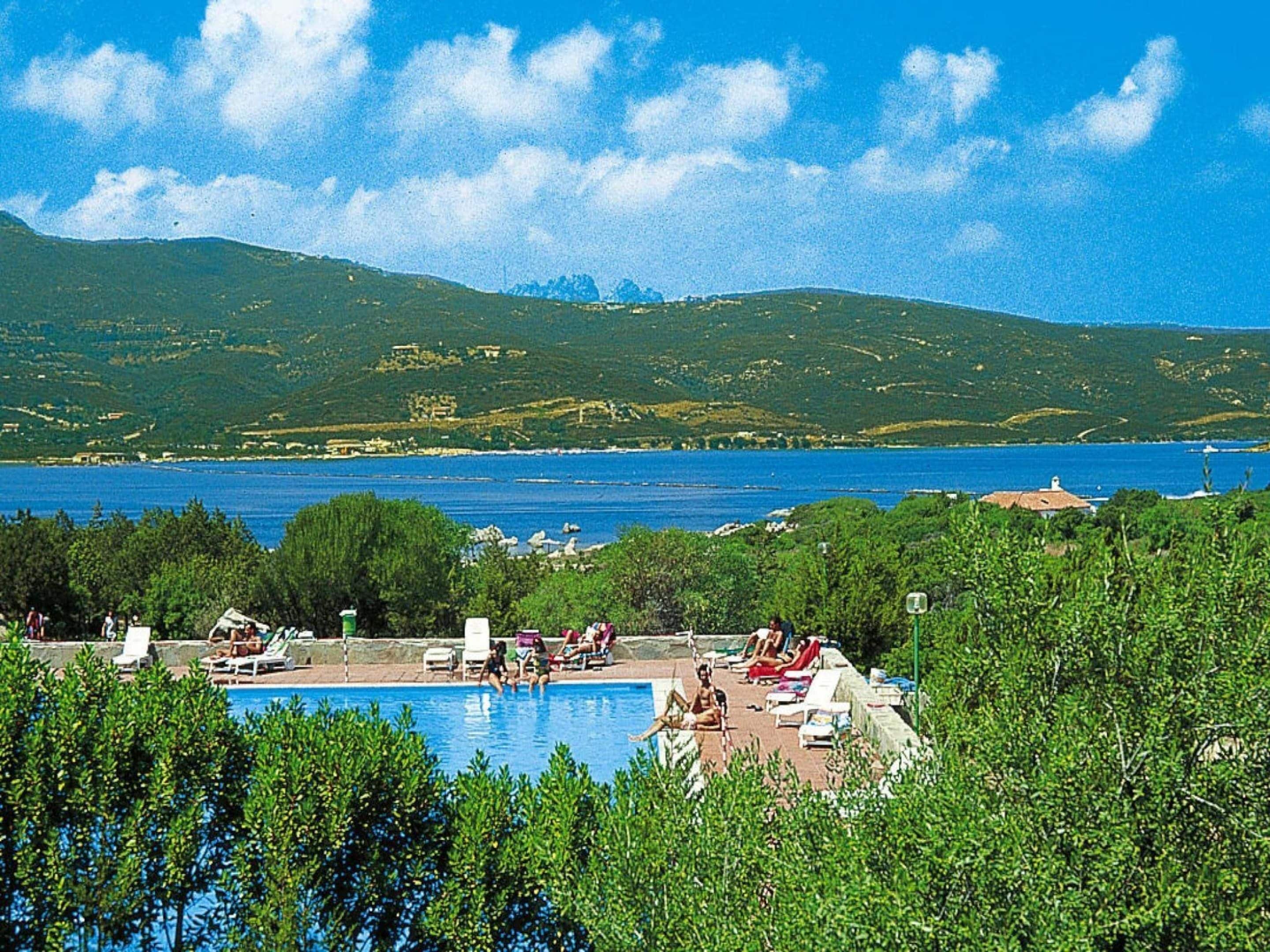 Zona de piscina amb gandules i vista al mar i a les muntanyes.