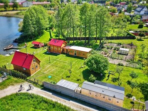 A residential area with a large building, a small house with a red roof, and a pond. - Cottage by Ostrowieckie Lake With Private Beach (Malechowo)