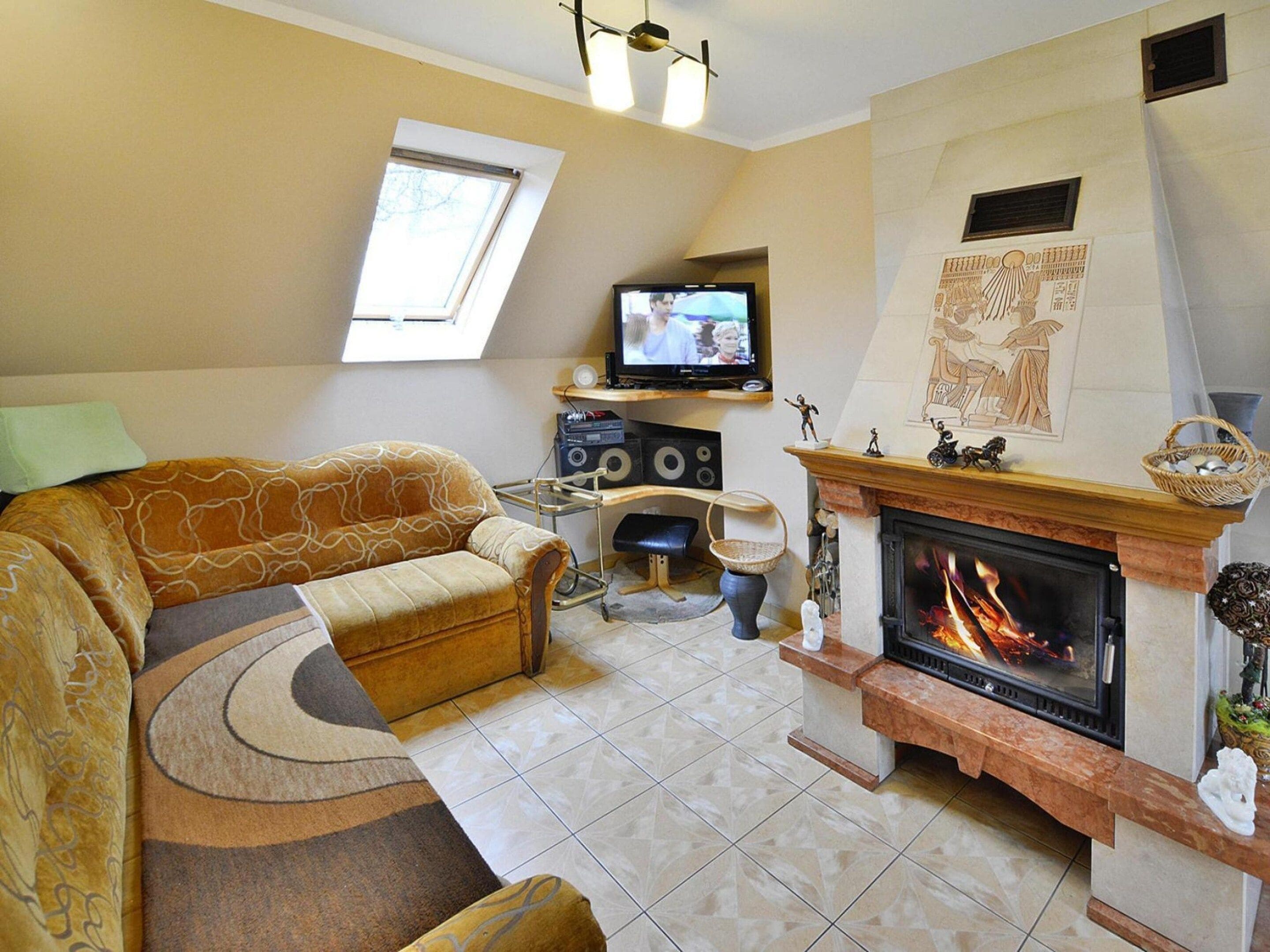 A living room with a sofa, a fireplace, a television, and a window.