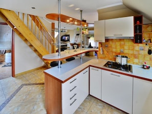 A modern kitchen with a central island, wooden staircase, and a tiled backsplash. - Cottage by Ostrowieckie Lake With Private Beach (Malechowo)