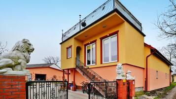 A two-story building with a yellow facade, a balcony, and a lion statue at the entrance.