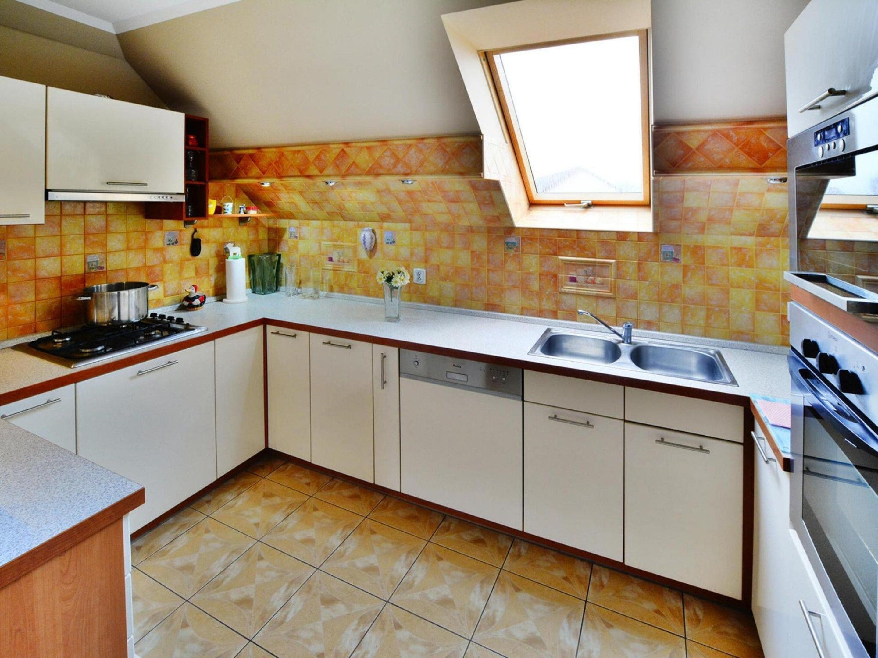Una cocina con horno integrado, un lavamanos y una ventana sobre la encimera.