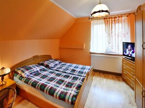 A bedroom with a bed, a television, a dresser, and a window with curtains. - Cottage by Ostrowieckie Lake With Private Beach (Malechowo)