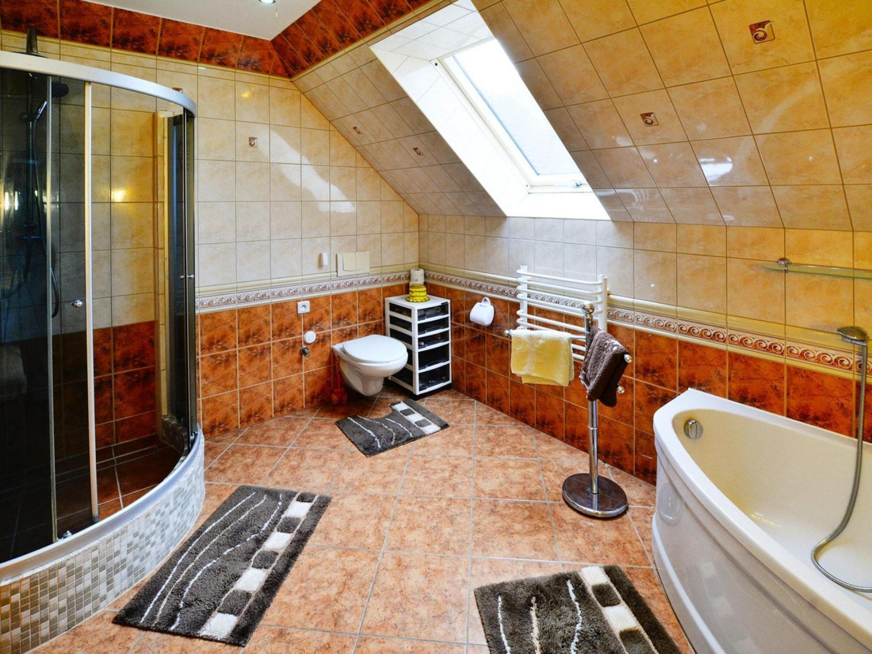 A bathroom with a shower, toilet, bathtub, and a skylight.
