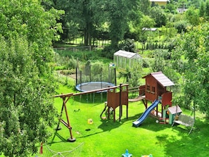 A fenced outdoor play area with a swing set, slide, and climbing structure. - Cottage by Ostrowieckie Lake With Private Beach (Malechowo)