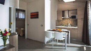 Une chambre d’hôtel moderne dotée d’un coin repas, d’une cuisine et d’une salle de bain.