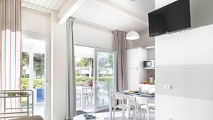 Une cuisine moderne avec des meubles blancs, une table à manger avec des chaises et un téléviseur fixé au mur.