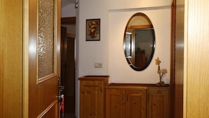 A hallway with wooden cabinets, a mirror, and a floral painting on the wall. - Apartment in Zillertal Near Horbergbahn (Hippach)
