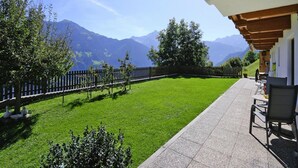 A terrace with a view of mountains, a wooden fence, and outdoor seating. - Apartment in Zillertal Near Horbergbahn (Hippach)