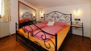 A bedroom with a bed, a nightstand, a mirror, and a window with curtains. - Apartment in Zillertal Near Horbergbahn (Hippach)