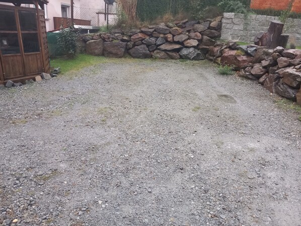 A gravel driveway leading to a wooden gate, surrounded by a stone wall and a wooden fence. - Ferienwohnung mit Garten in Reisbach Nähe Bayernpark (Reisbach)