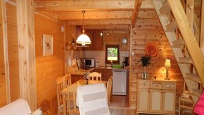 A cozy cabin interior with a dining area, kitchen, and a staircase. - Holiday House in Sarbinowo Near the Beach (Mielno)