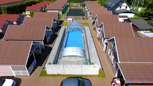 Una zona residencial con una piscina central, rodeada de casas con techos de tejas rojas.