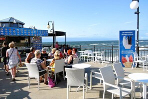 A seaside café with outdoor seating, a food truck, and a view of the ocean. - Holiday Homes With Swimming Pool, Miedzyzdroje (Międzyzdroje)